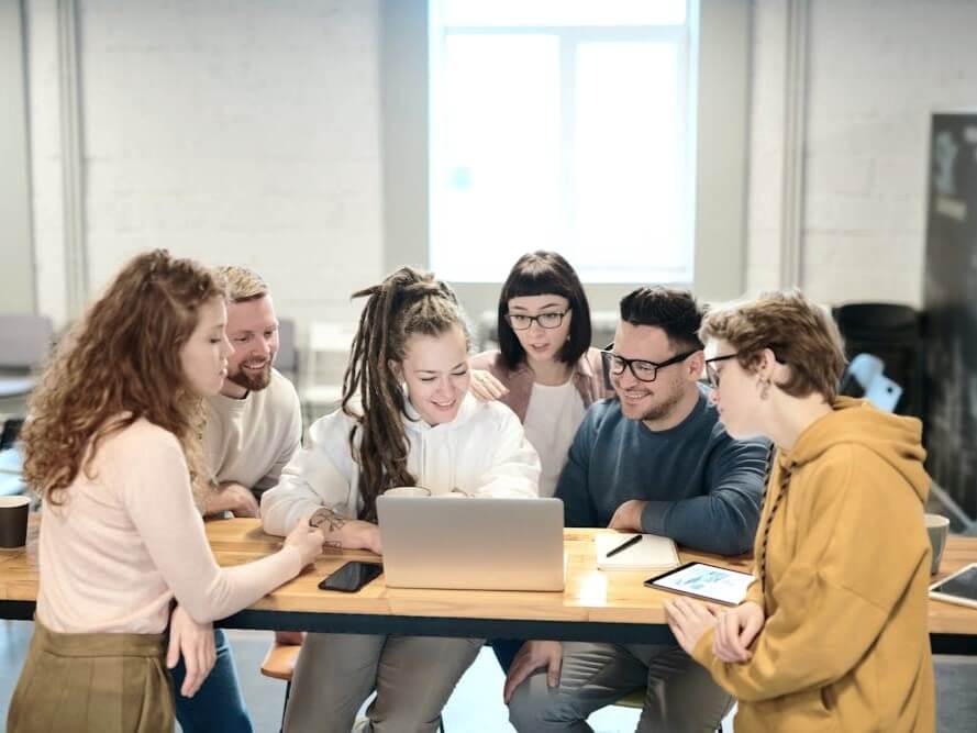 Team hundling together around computer.