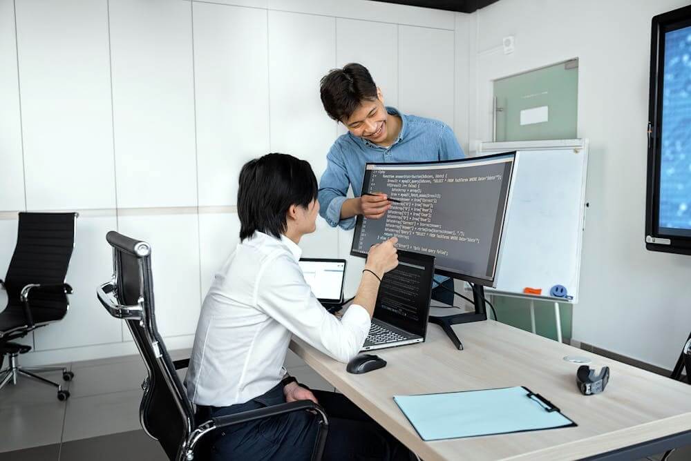 Teammates working on code together.