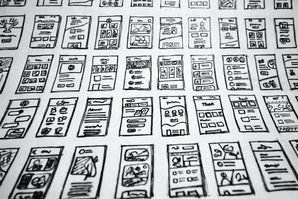Bunch of hand drawn wireframes for a mobile app on a sheet of paper.